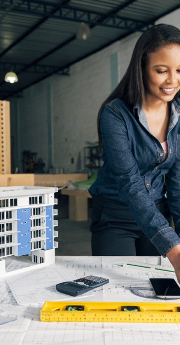 dame-afro-americaine-gaie-debout-pres-modele-construction-table