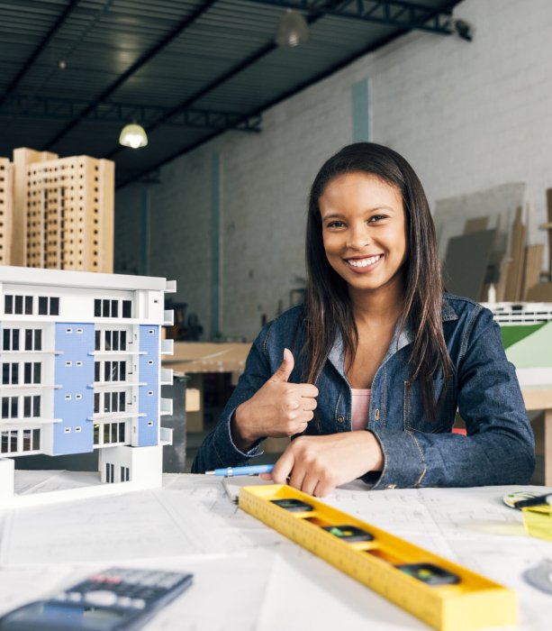 souriant-afro-americaine-femme-montrant-pouce-vers-haut-pres-modele-batiment